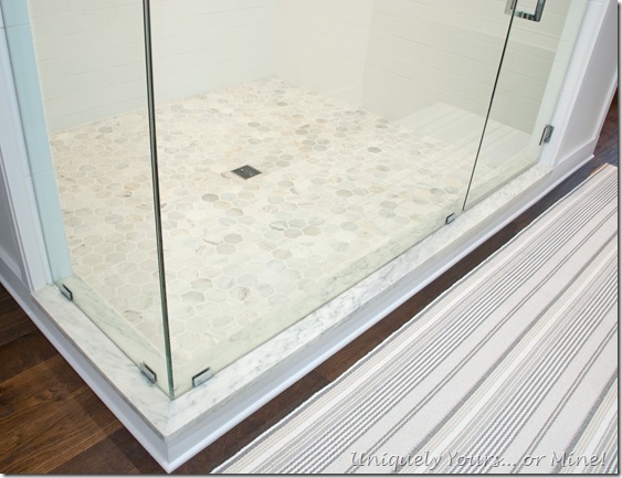 Master bathroom shower stall, white ceramic herringbone and subway with Carrera hexagon tile floors and White Mountain Danby Marble curb