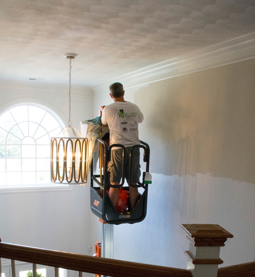 Painting walls in two story foyer with personal lift