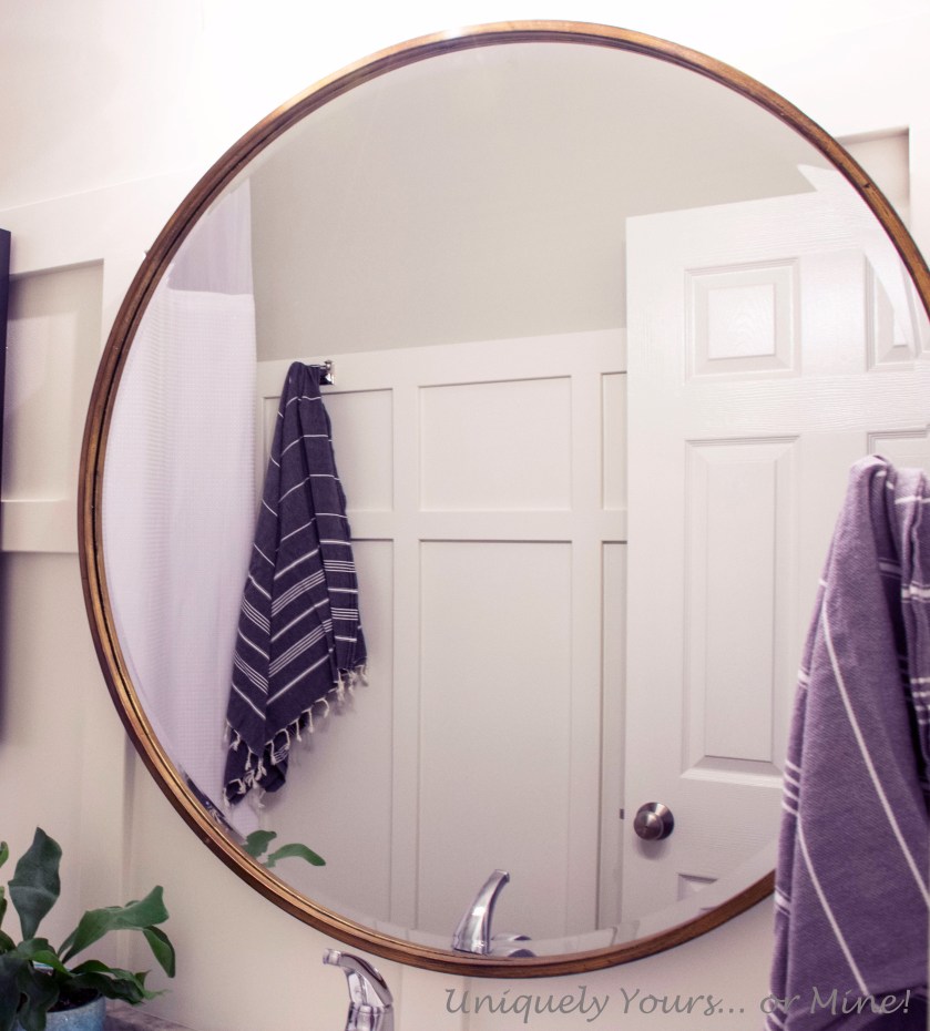 Board and batten DIY in guest bathroom, large round brass mirror